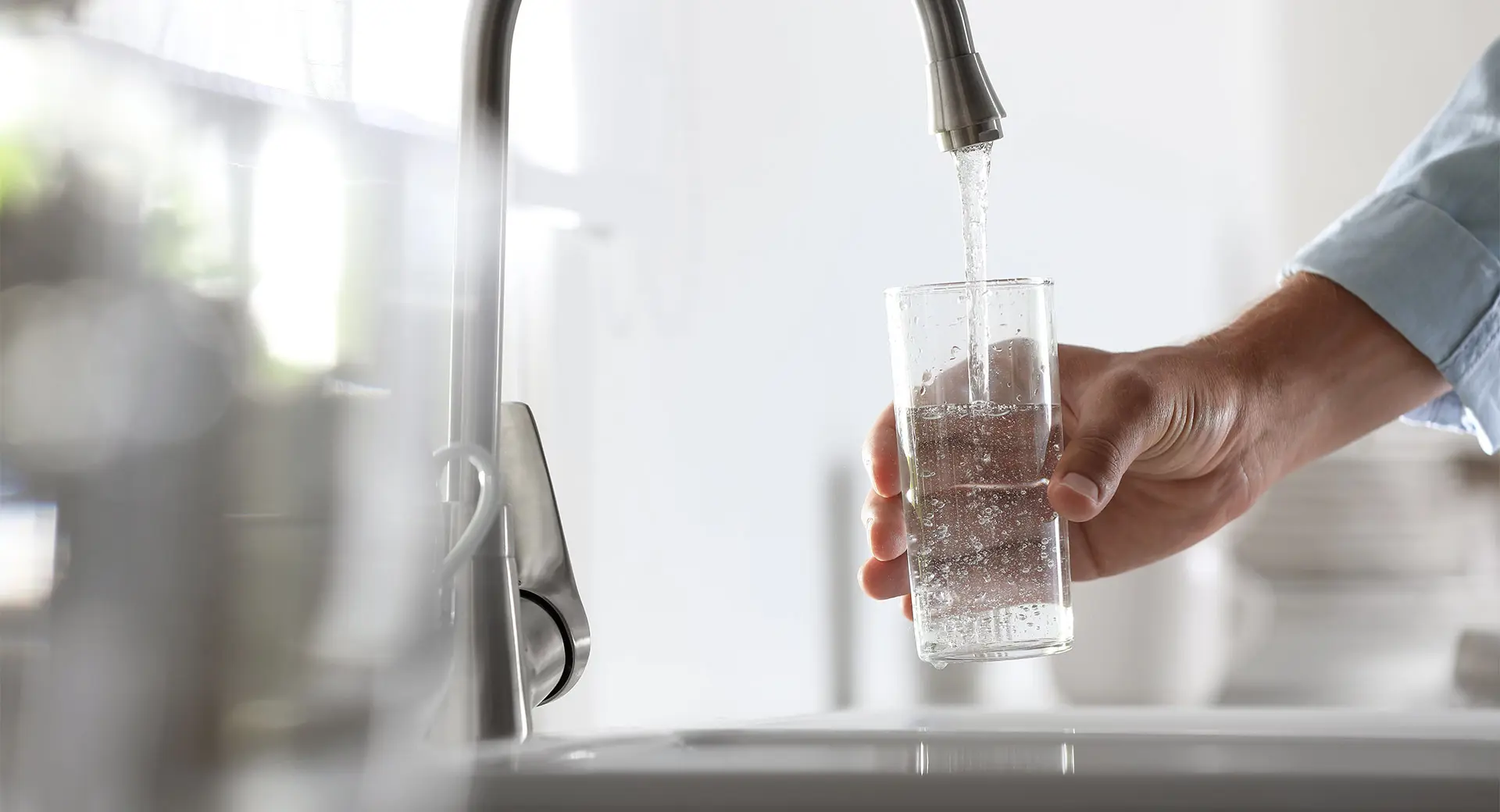 Person filling a glass with tap water 