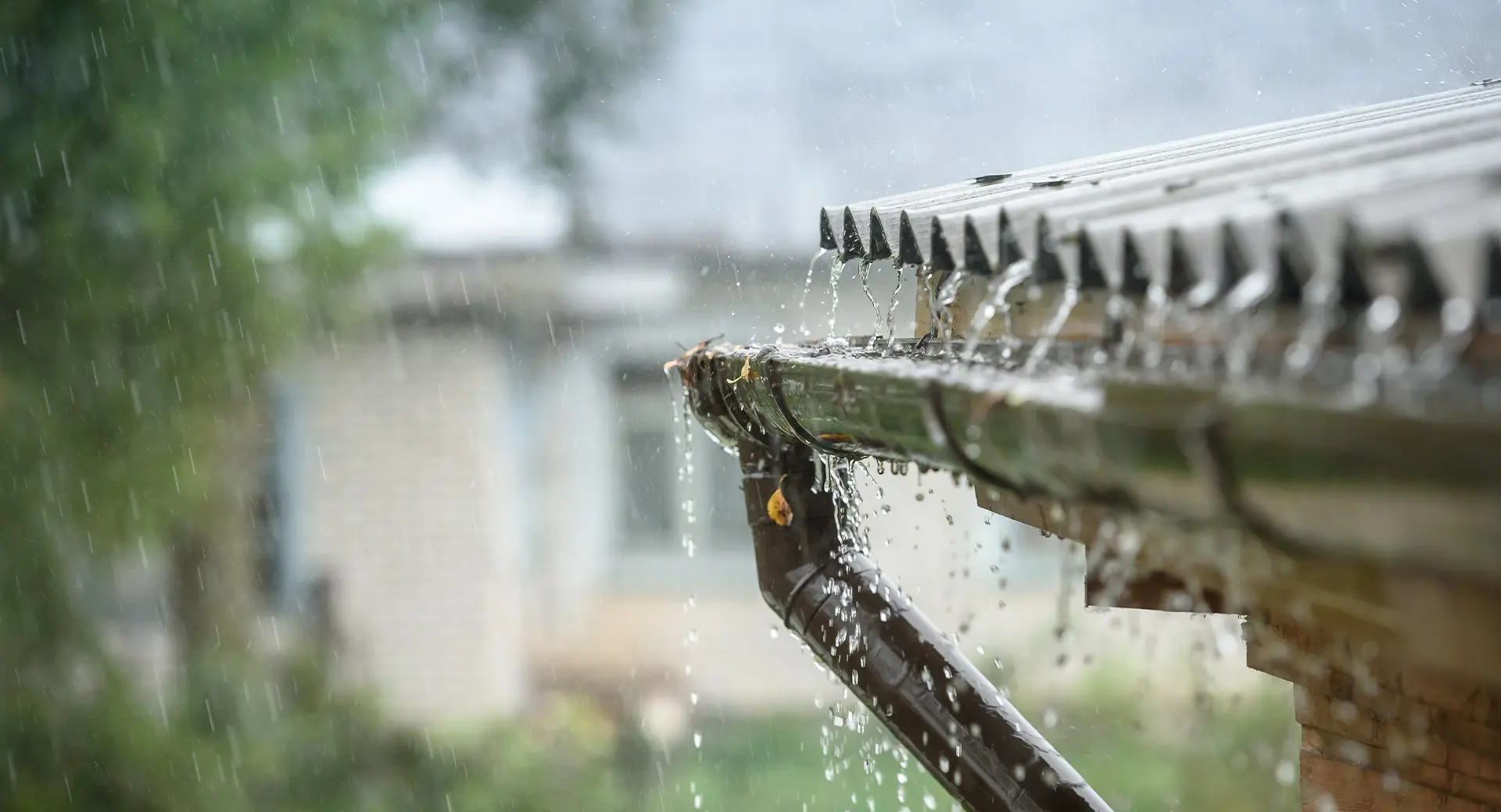 Rain pours off a roof into an overflowing gutter